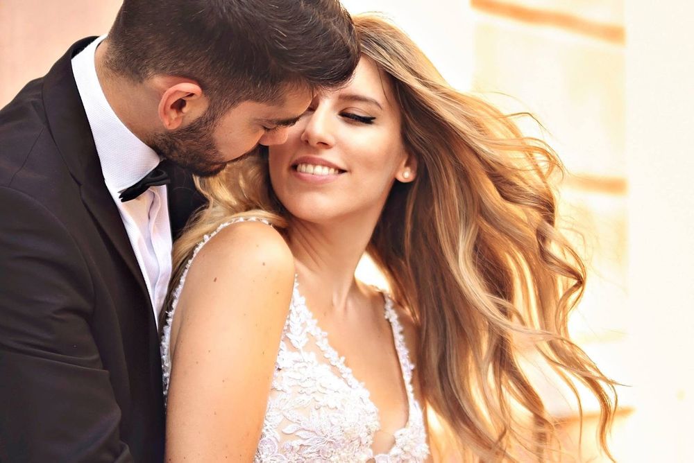 A romantic couple in wedding attire embrace while sharing a tender moment together outdoors.