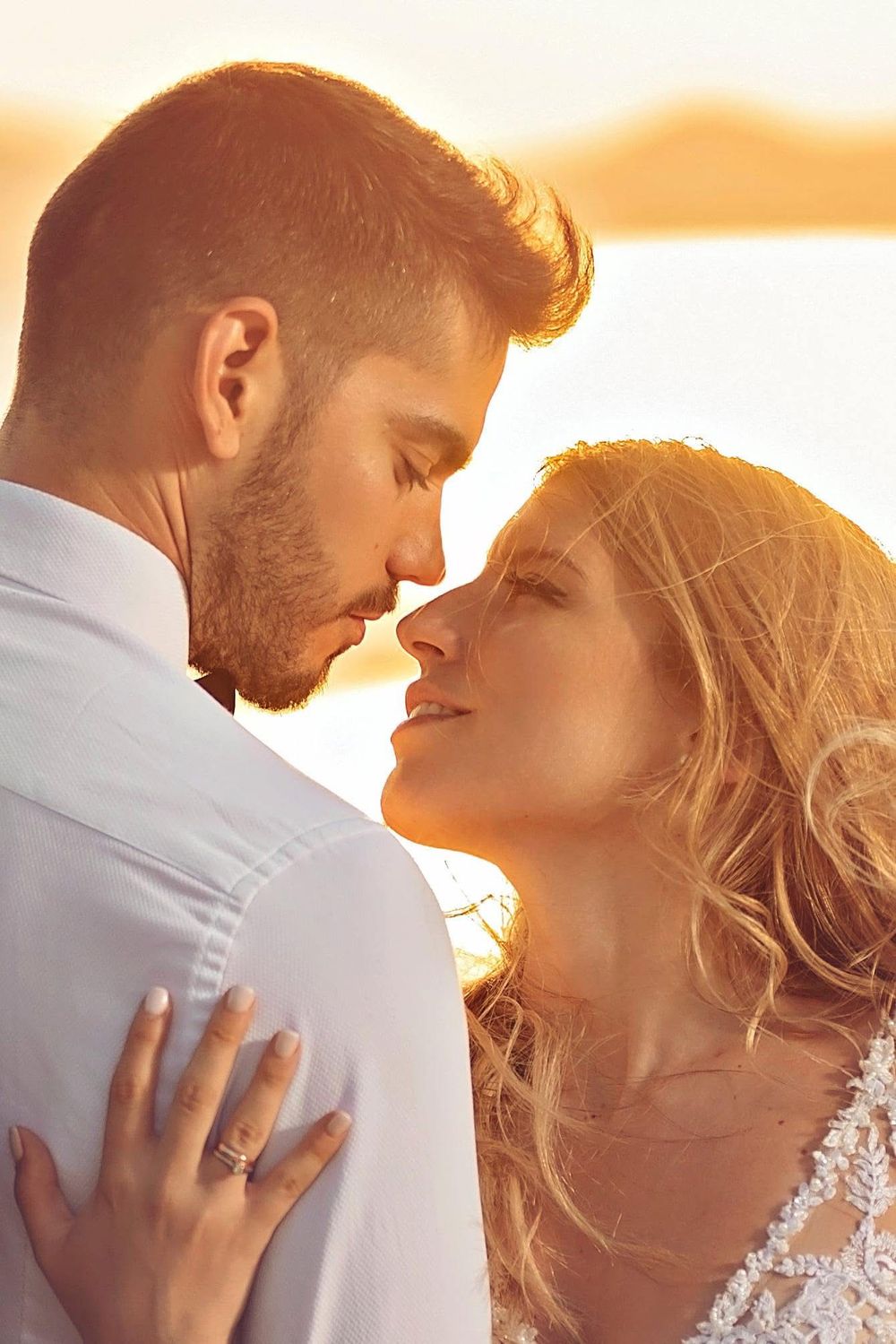 Intimate sunset portrait of newlyweds in a tender embrace with soft golden lighting.