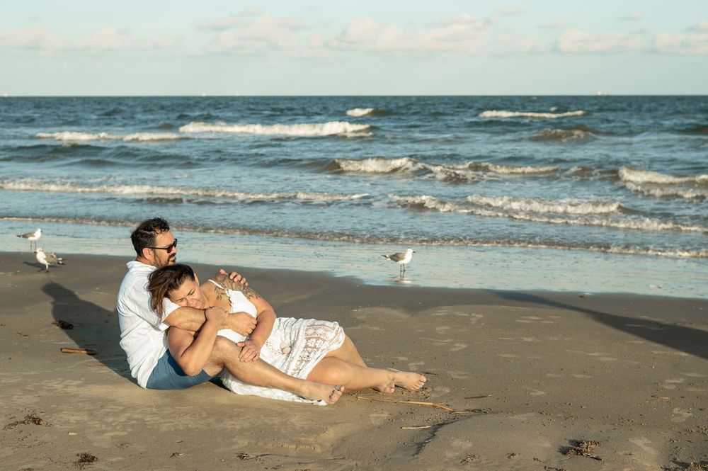A seaside photoshoot and wedding scene with waves crashing in the background at a sandy coastal beach.
