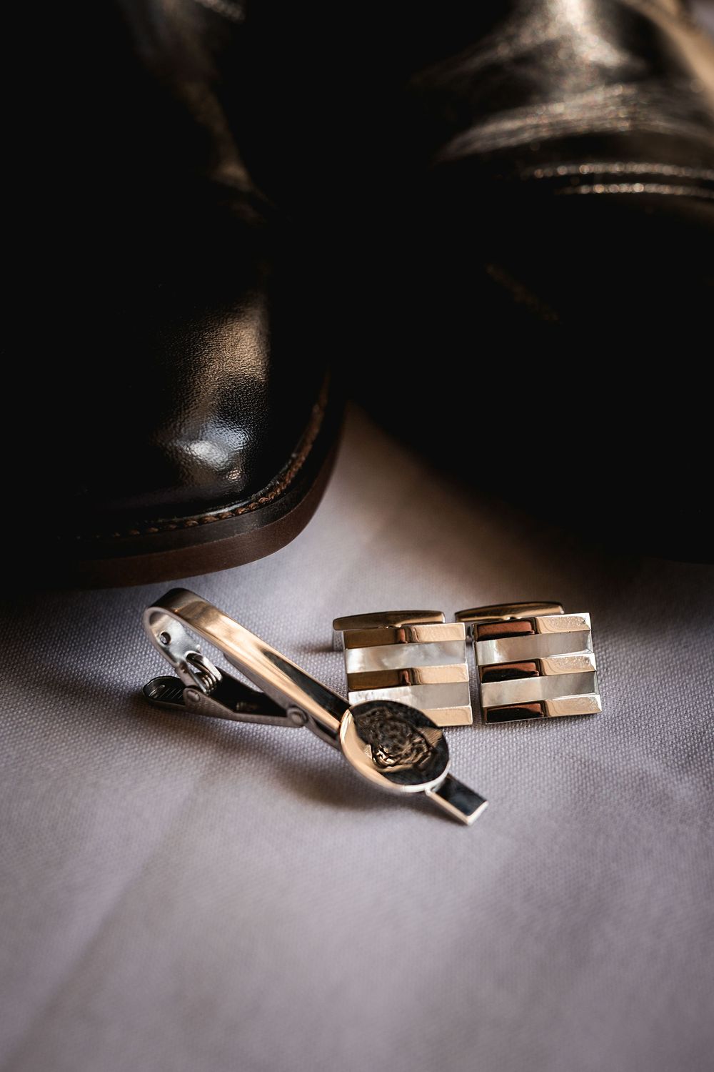 Elegant gold wedding cufflinks and rings arranged artistically on a gray surface in dramatic lighting.