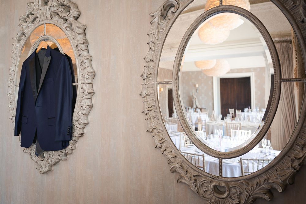 Ornate vintage mirrors with decorative frames adorn a light-colored wall in an elegant room setting.