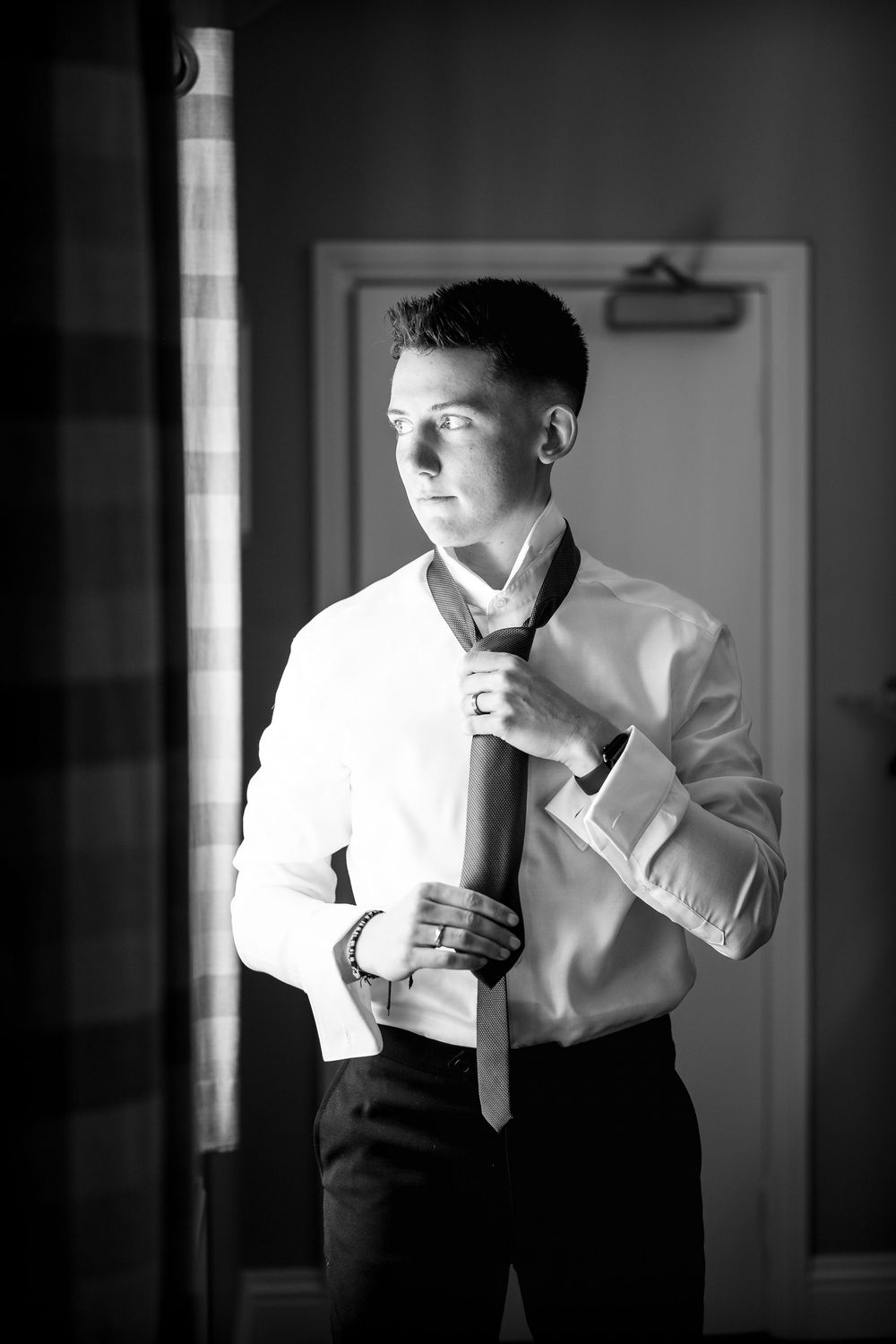 A sequence of black and white photos showing someone adjusting their tie while getting dressed.