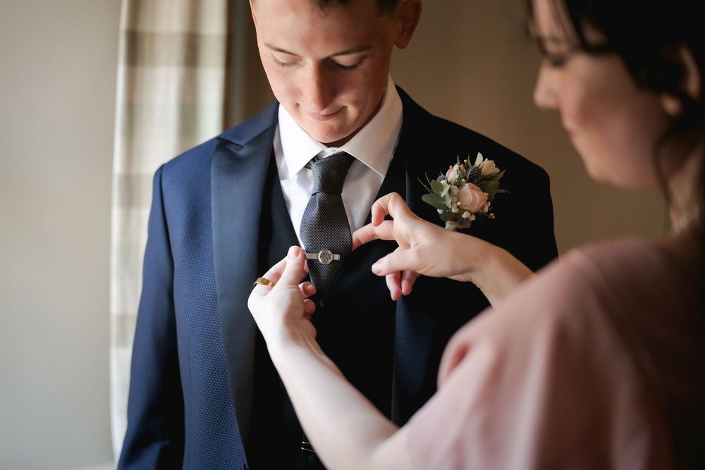 Intimate moment showing formal attire and boutonniere preparations.