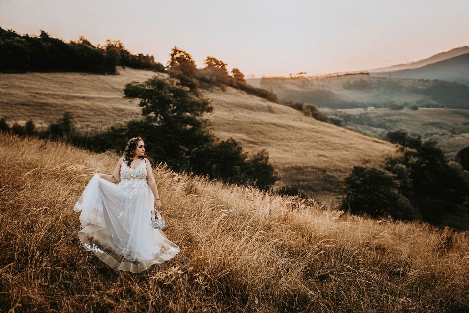 Bridal portrait of blonde bride in Corinth, Texas hills at golden hour with long embroidered veil.