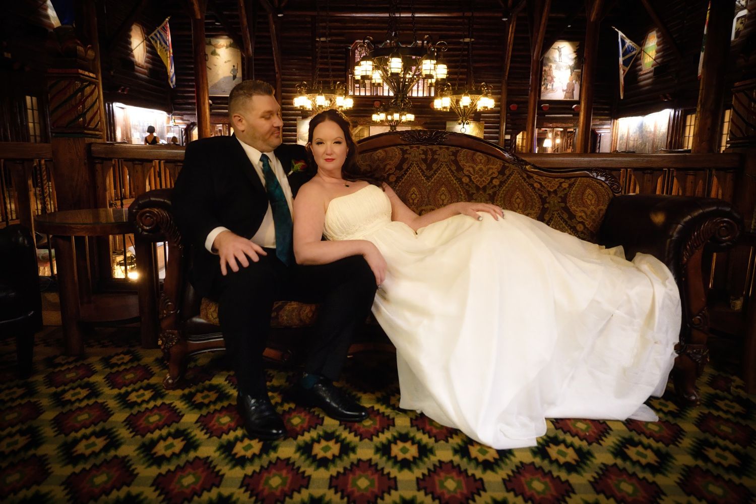 Wedding couple dances together in elegant ballroom under vintage chandeliers.