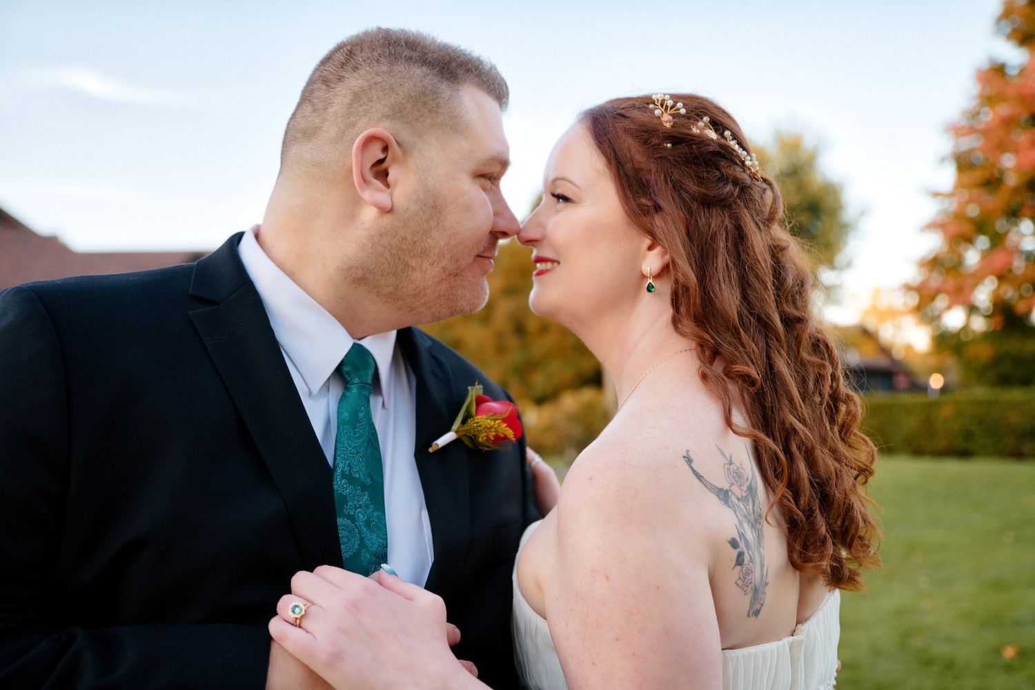 A couple shares a tender moment during their autumn outdoor wedding celebration.