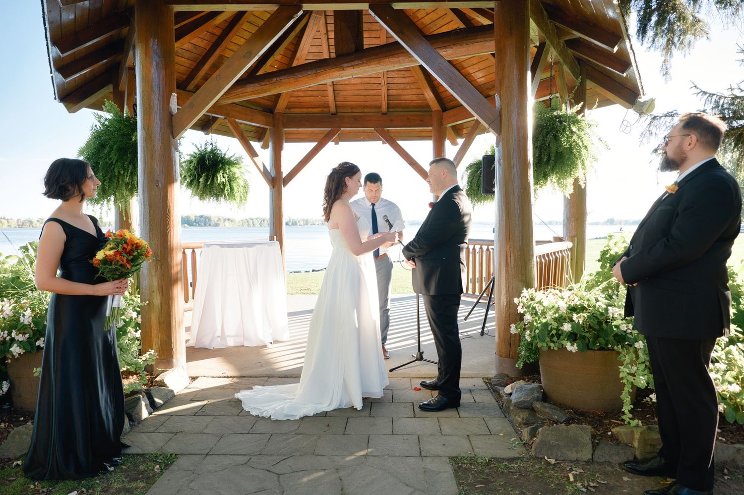 Wedding ceremony setup at a covered outdoor venue with wooden beams and natural lighting.