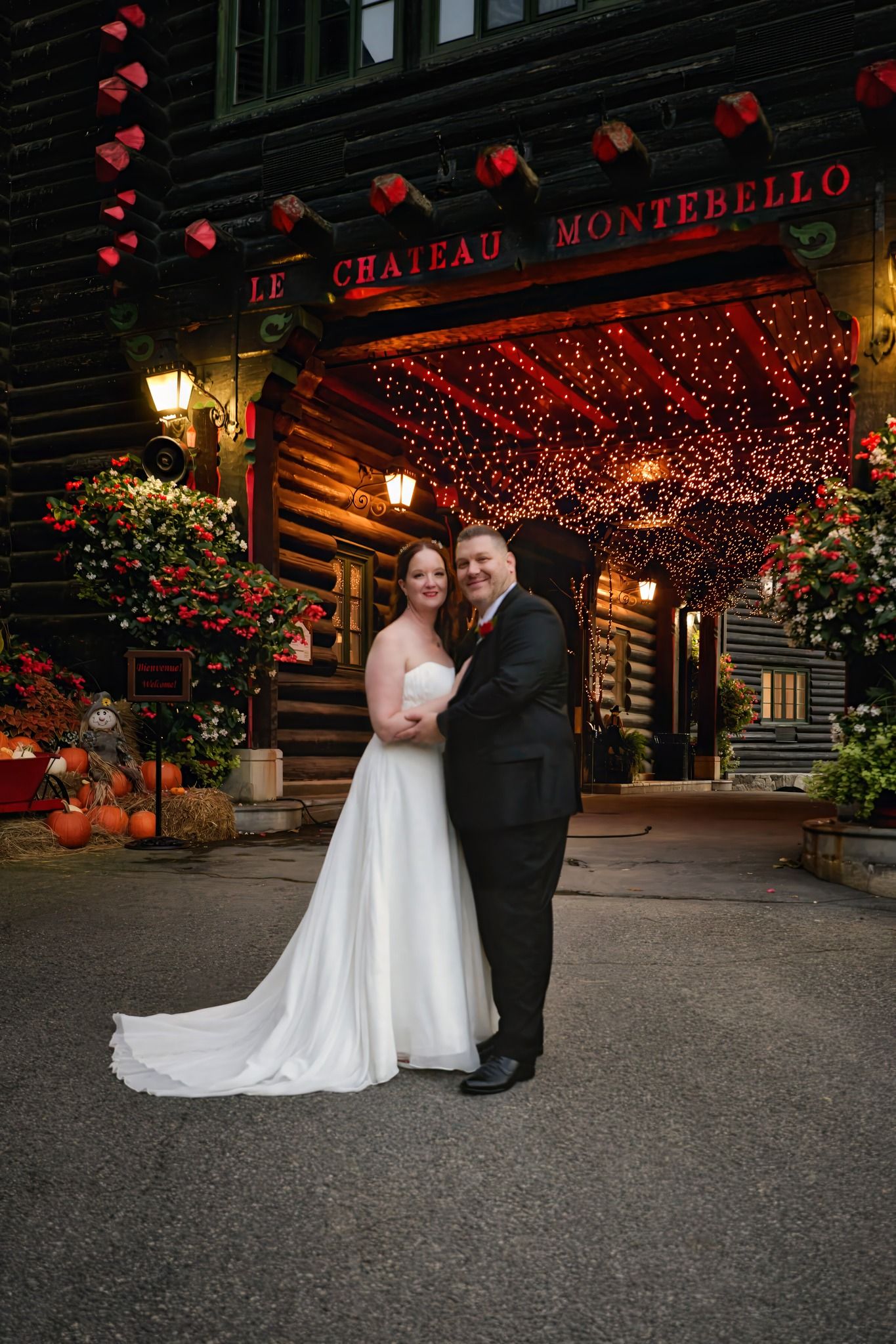 A couple shares a romantic moment under twinkling red lights outside Montebello building at night.