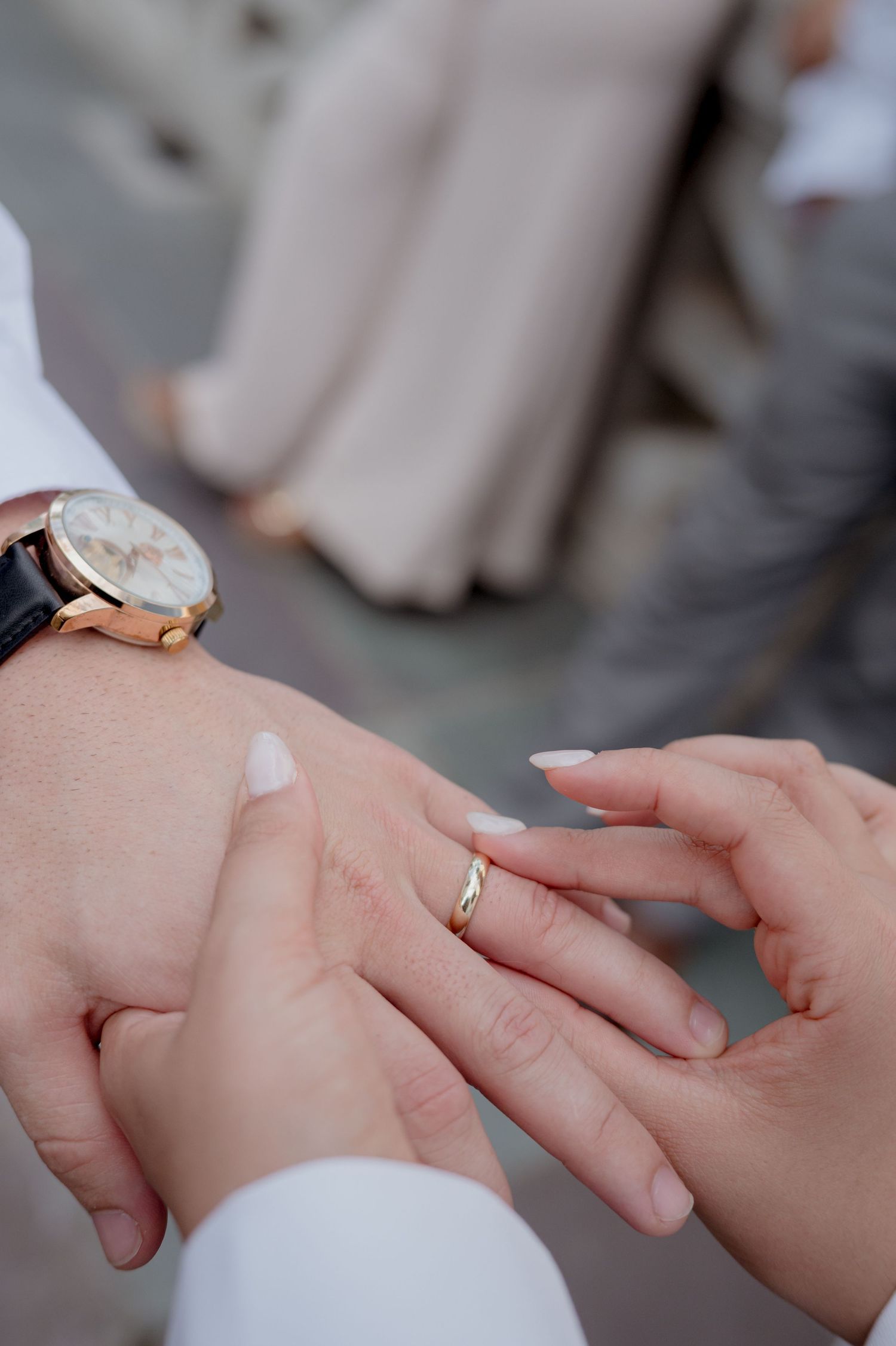 Close-up view of hands during a wedding ring exchange ceremony showing both bride and groom's hands at the altar.