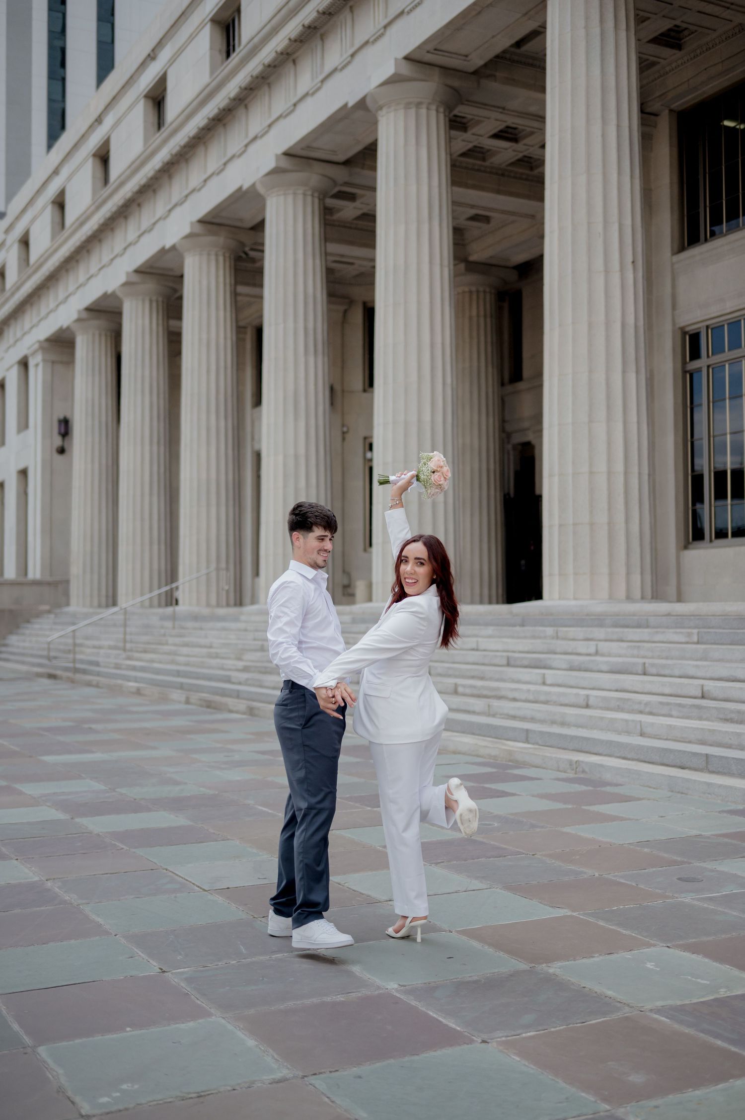 A romantic proposal moment on the grand steps of a building with classical columns in the background.