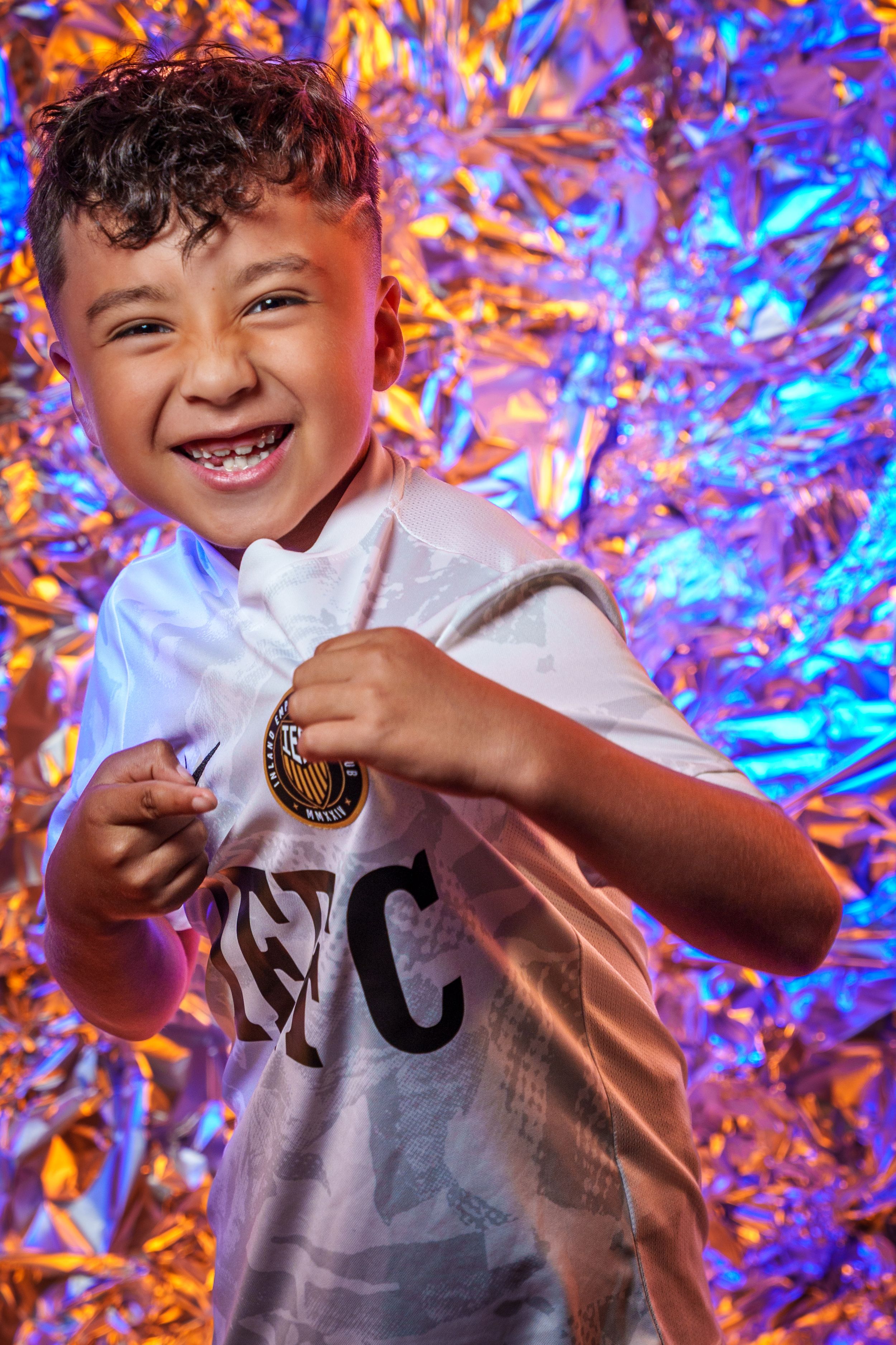 Soccer merchandise photoshoot with white jersey against colorful metallic backdrop.