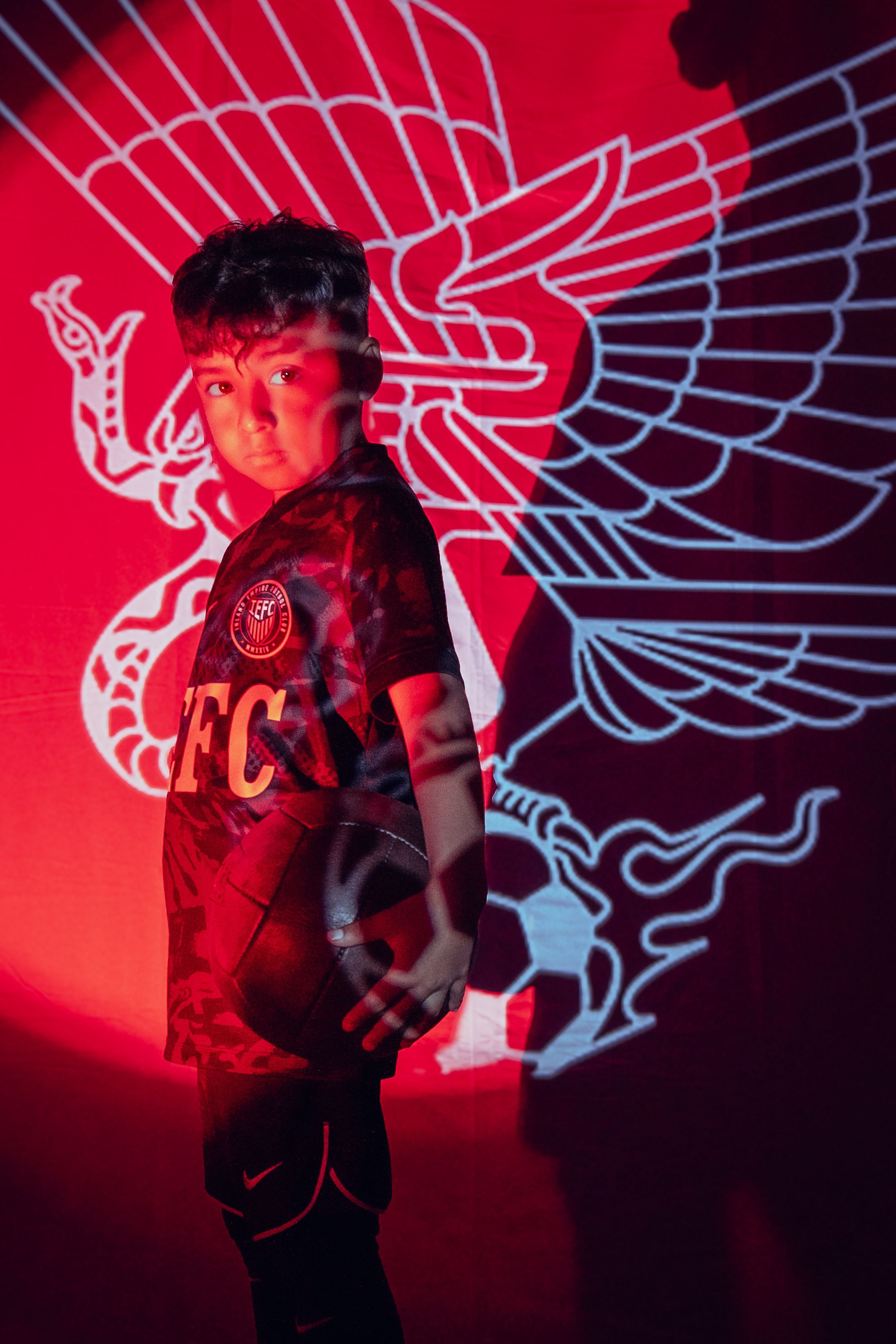 Athletic wear photographed against red background with wing logo design.