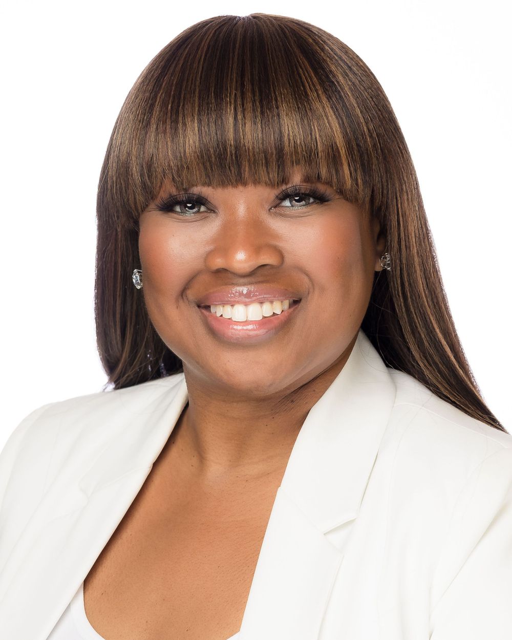 Professional headshot of person in white blazer with styled hair against white background.  Mika Larson Photography.