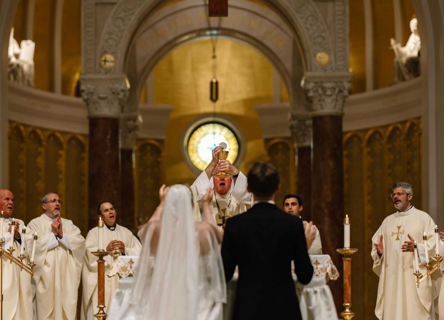 An ornate church interior during a wedding ceremony with golden lighting and classical architecture.