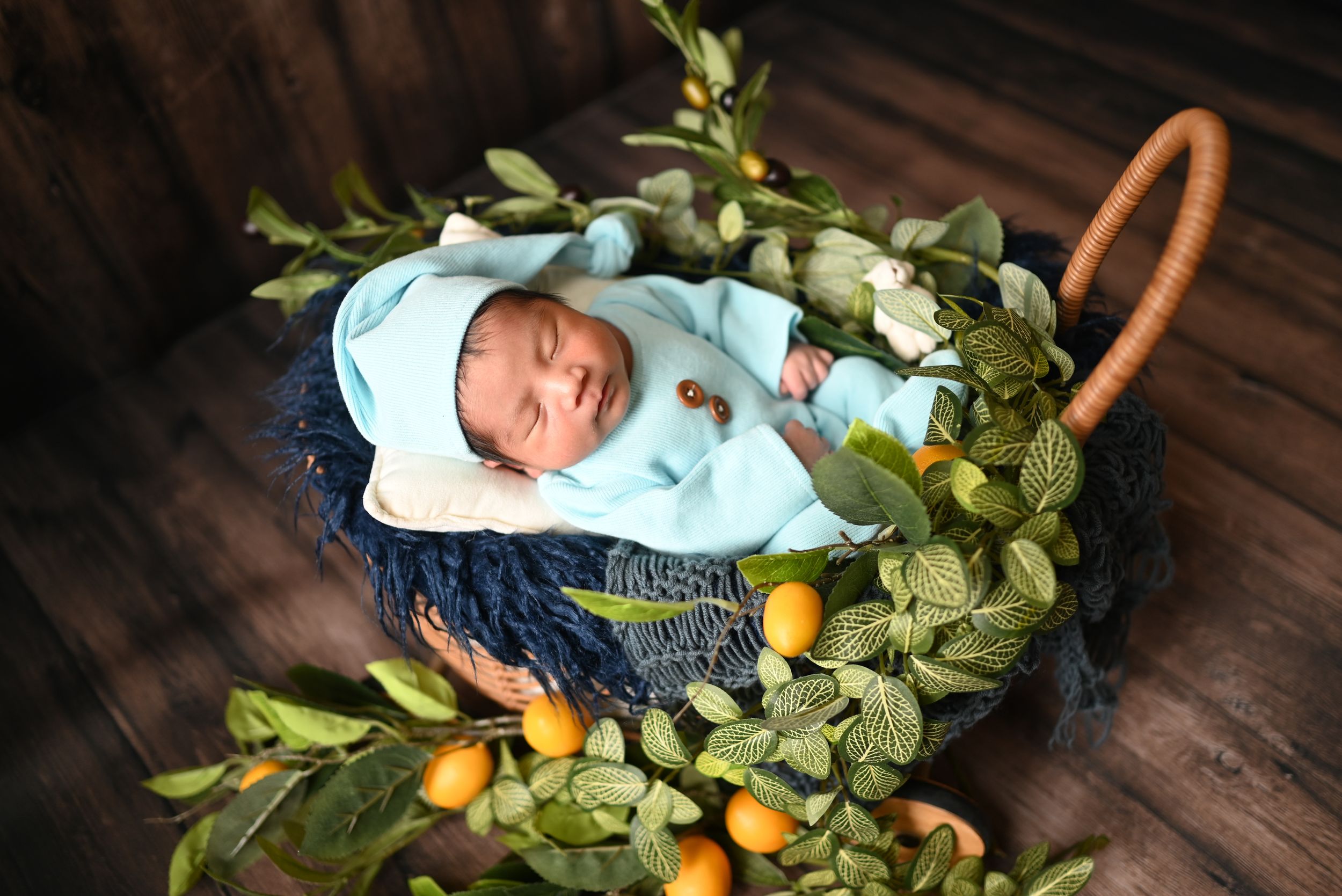 Fresh citrus fruits and leaves arranged in a ring shape on a dark wooden surface create a festive holiday wreath.
