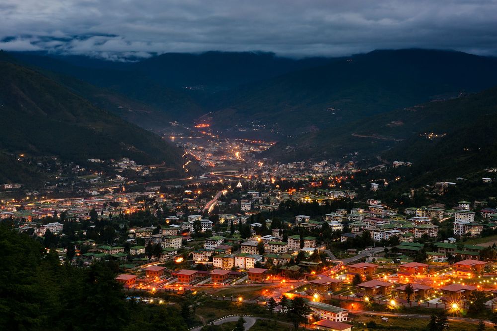 Time-lapse sequence of storm clouds rolling over a mountainous city at dusk showing dramatic lighting changes.