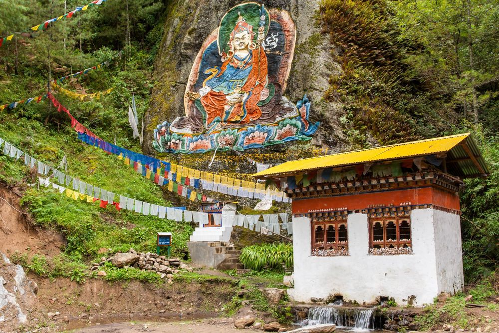 Scenic panorama of Tibetan Buddhist temples and meditation retreat buildings nestled along a forested mountain slope.
