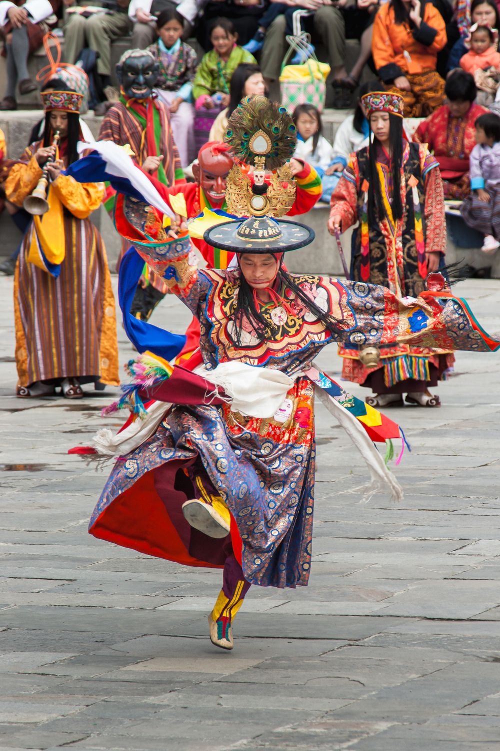 Traditional masked dancer performs colorful Cham dance at Buddhist festival in traditional ornate costume and headdress.