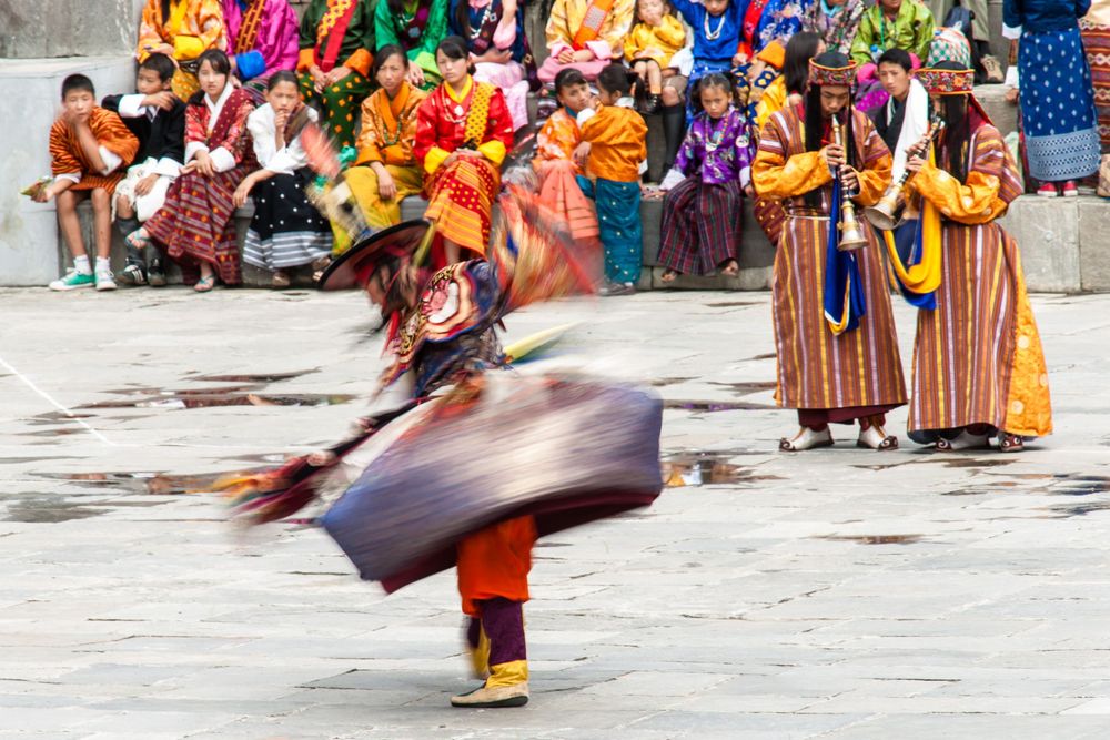 Colorfully dressed street performers dancing in traditional costumes during a cultural festival celebration.