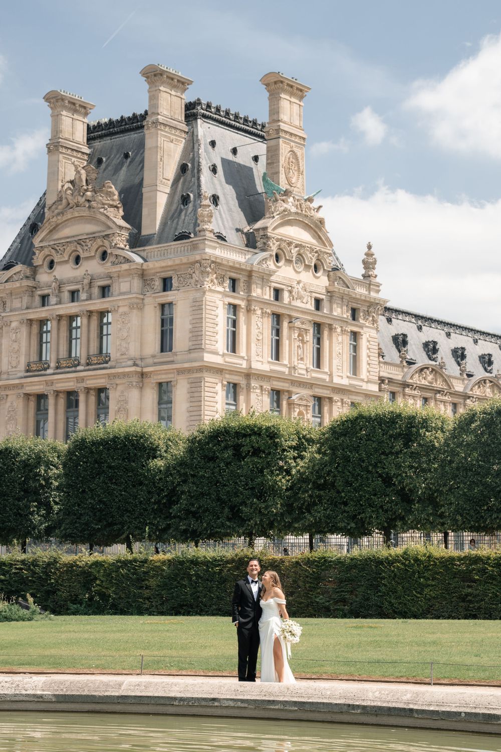 Wedding photos at Louvre gardens with classic French architecture backdrop.