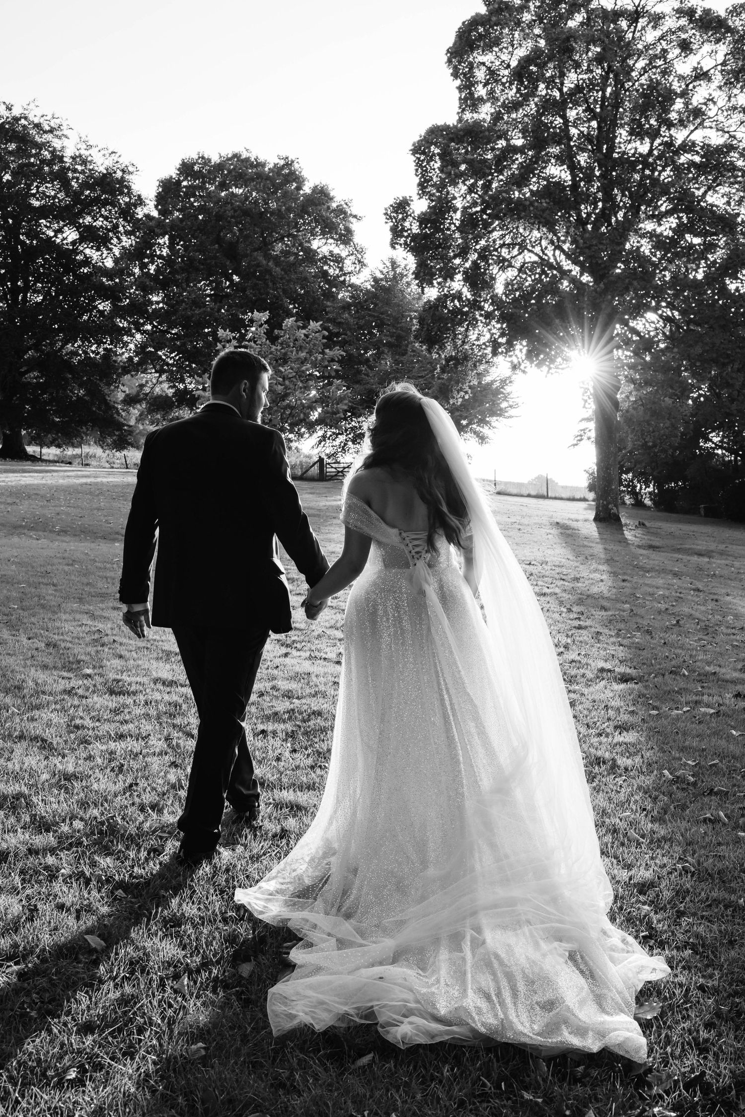 Coombe Lodge Wedding Photographer Zara Davis Photography black and white image of bride and groom walking towards sun romantic