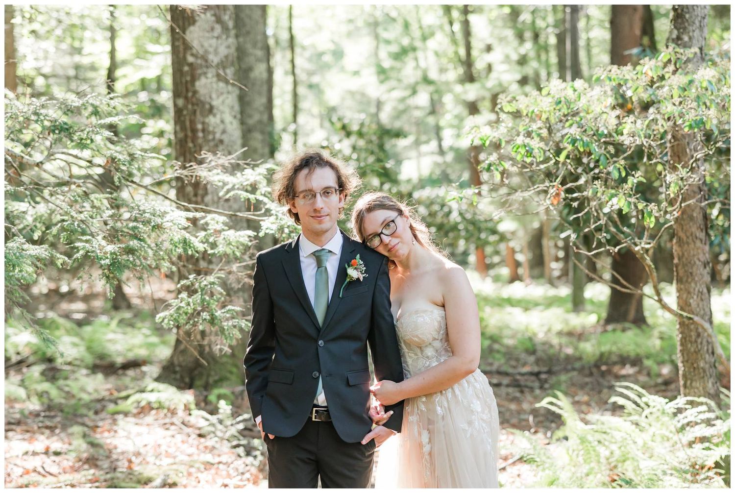 A romantic wedding photoshoot in a sunlit forest with the couple embracing among tall trees.