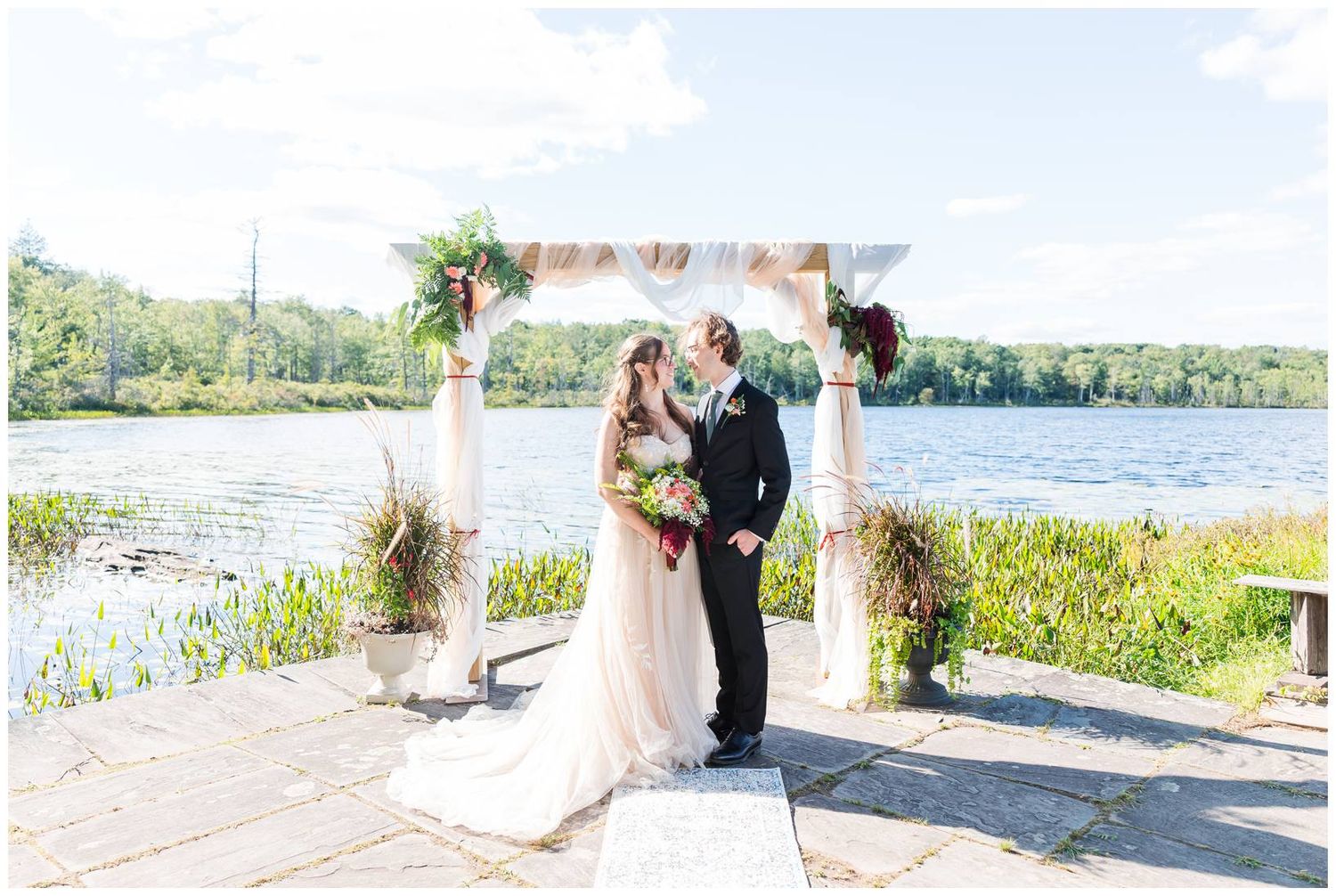 Scenic wedding ceremony setup by a lakeside with natural greenery and water views.