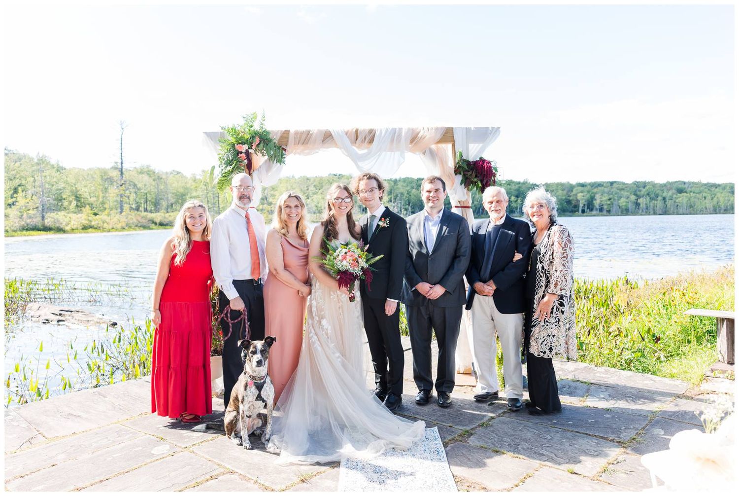 Waterfront wedding ceremony setup with guests gathered along a scenic lakeside path.
