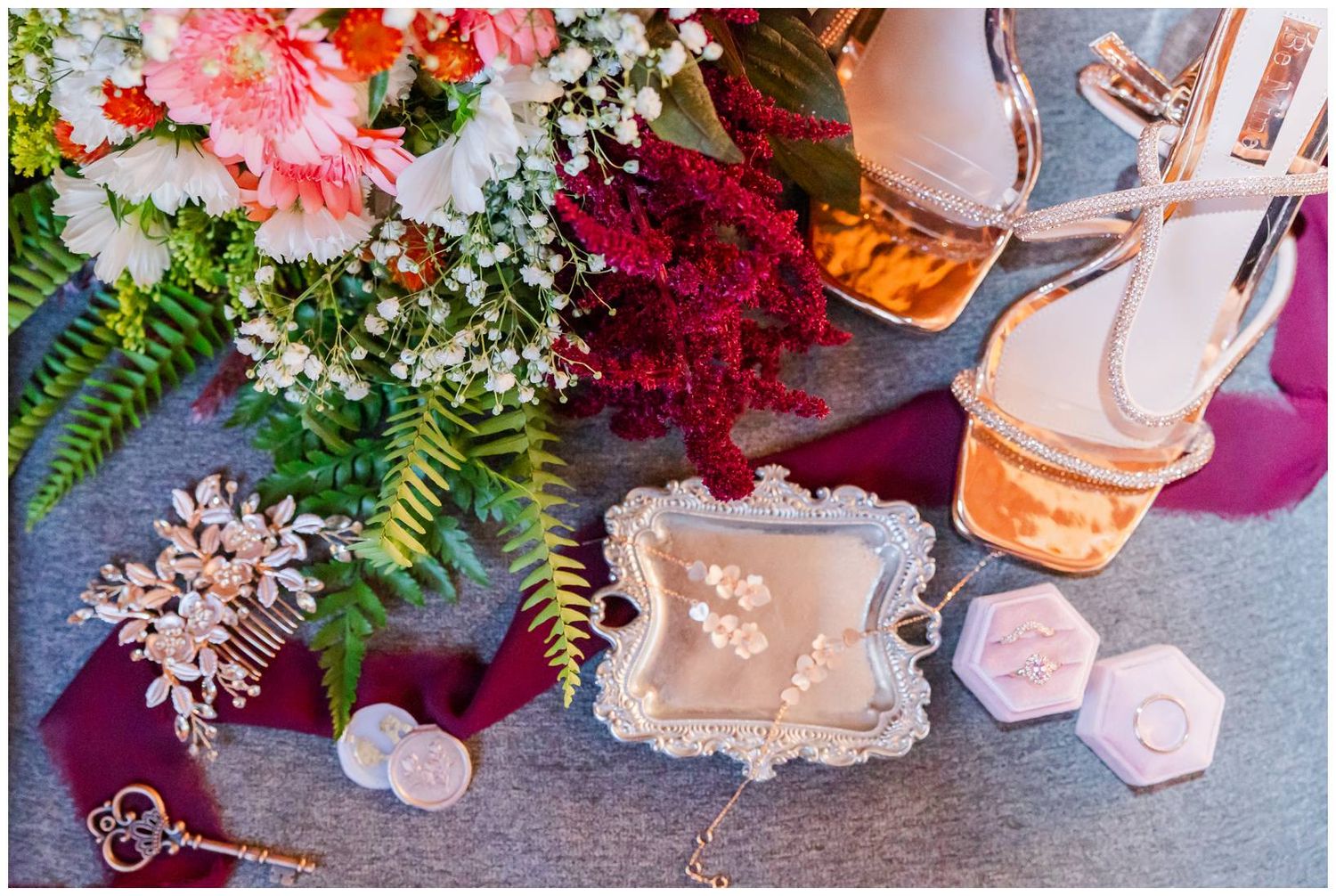 A collage of pink and red flowers arranged with candles and decor items on a grey surface.