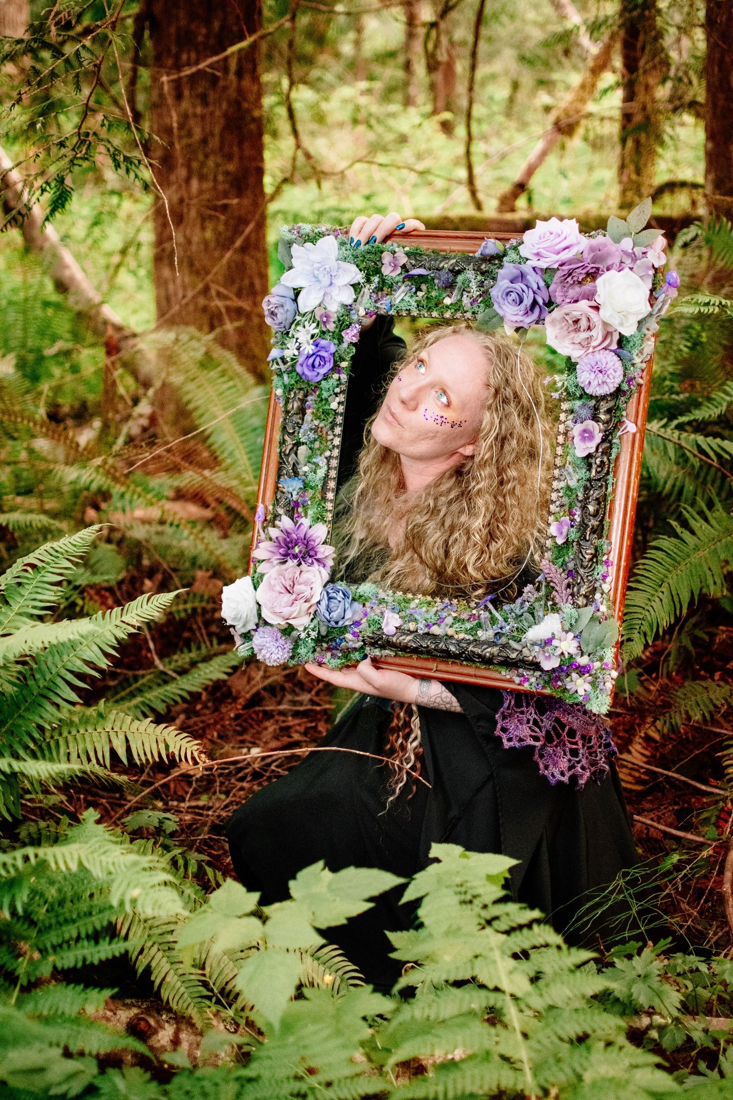 Model in black gown posing with floral mirror prop at The Pole Garden styled shoot.