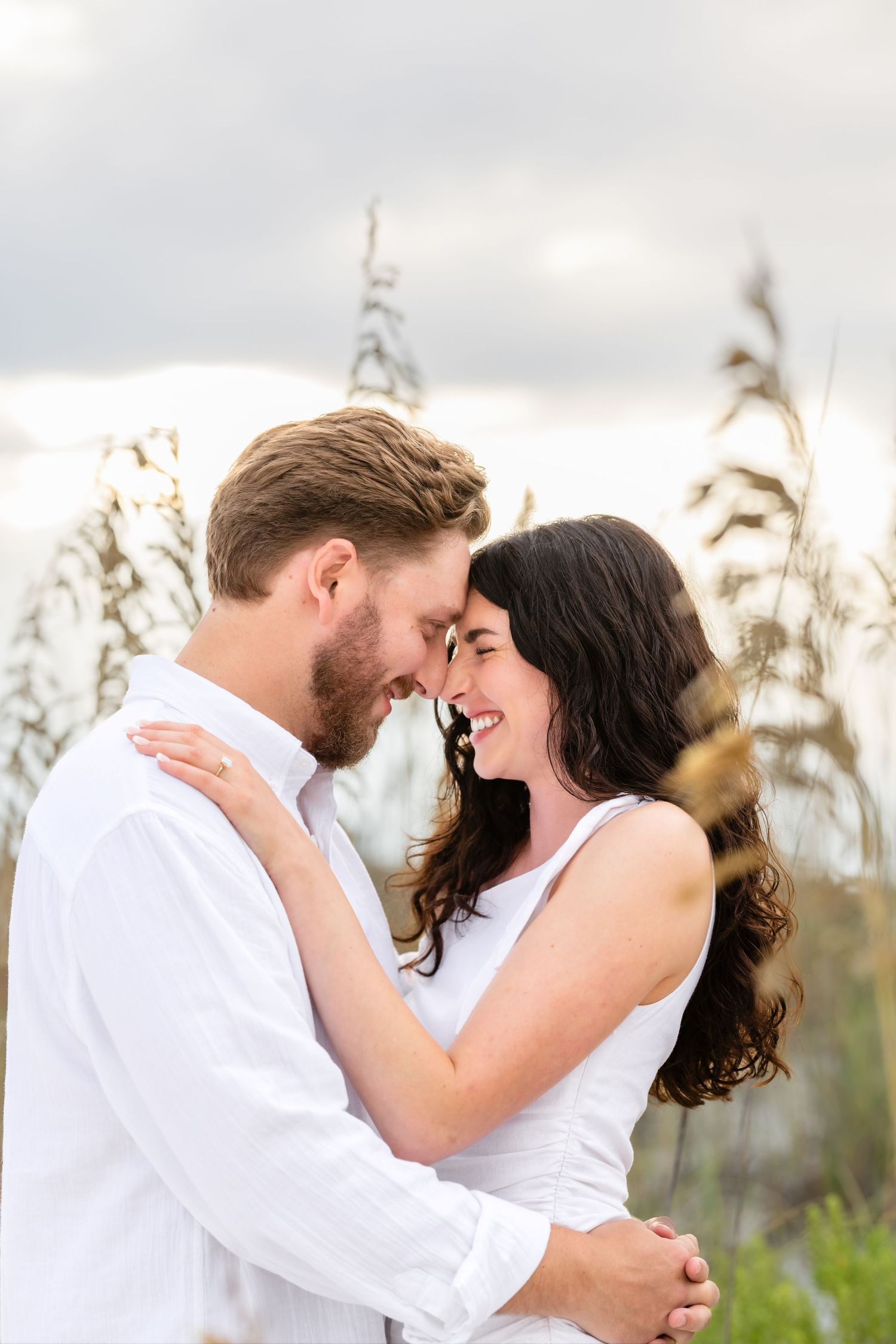 Romantic couple shares tender moments in a series of sunset photos with tall grass and natural light in the background.