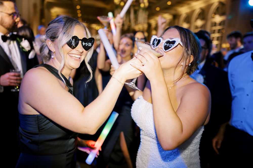 Guests dance close together on a dimly lit dance floor during a wedding reception celebration.