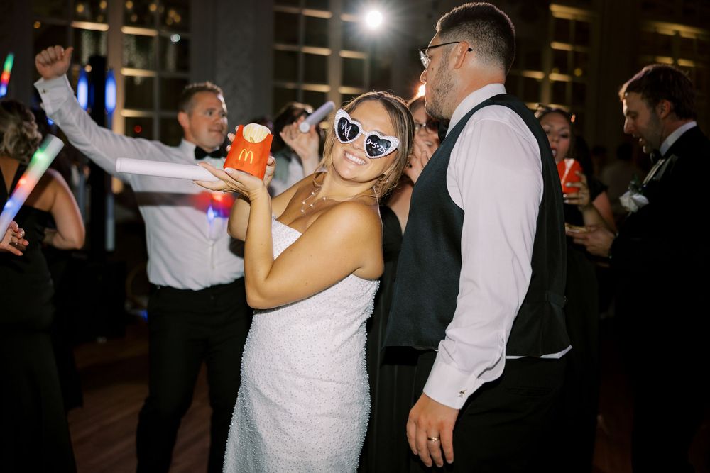 Wedding guests dancing and celebrating on a dimly lit dance floor at a reception party.