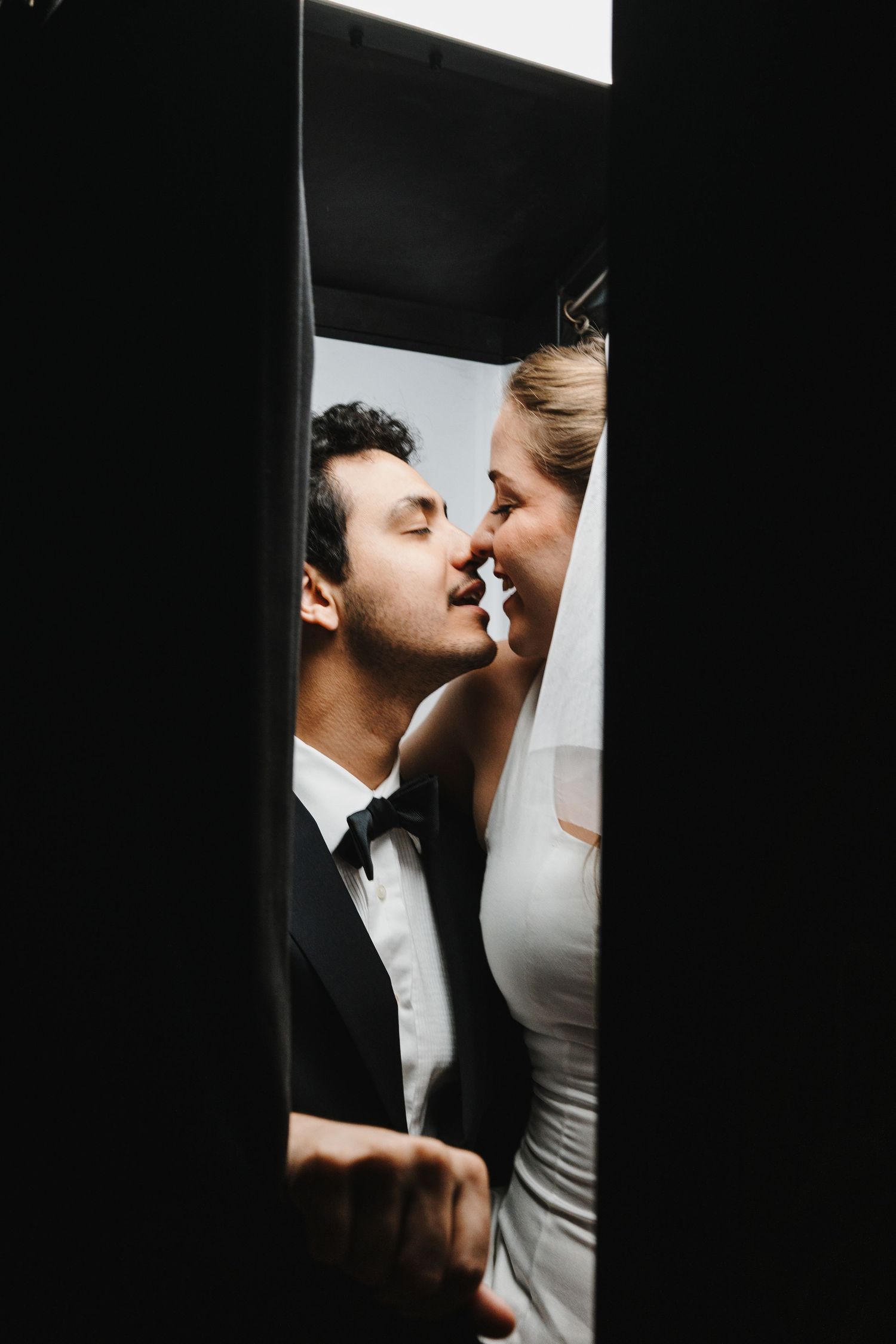 A romantic black and white wedding portrait shows an intimate moment between a couple in formal attire.