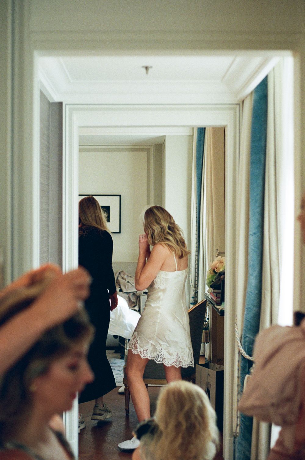 Multiple reflections in mirrored walls show people walking down an elegant hotel hallway with white trim and blue accents.