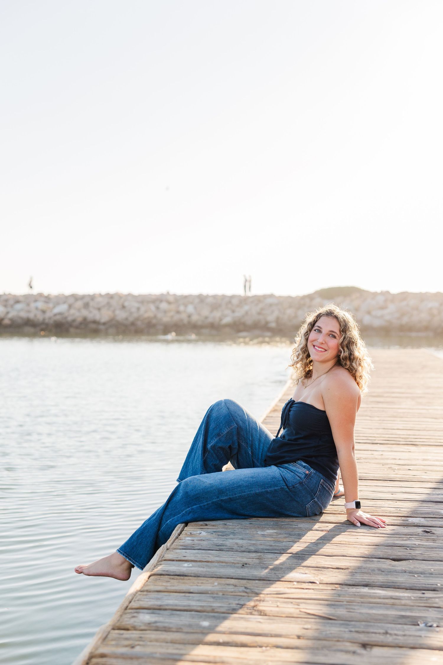 A series of photos showing someone laying on a wooden dock by the water at sunset.