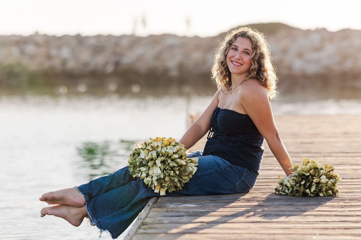 A person in a navy blue dress sits gracefully on stone steps while holding a bouquet of white and green flowers.
