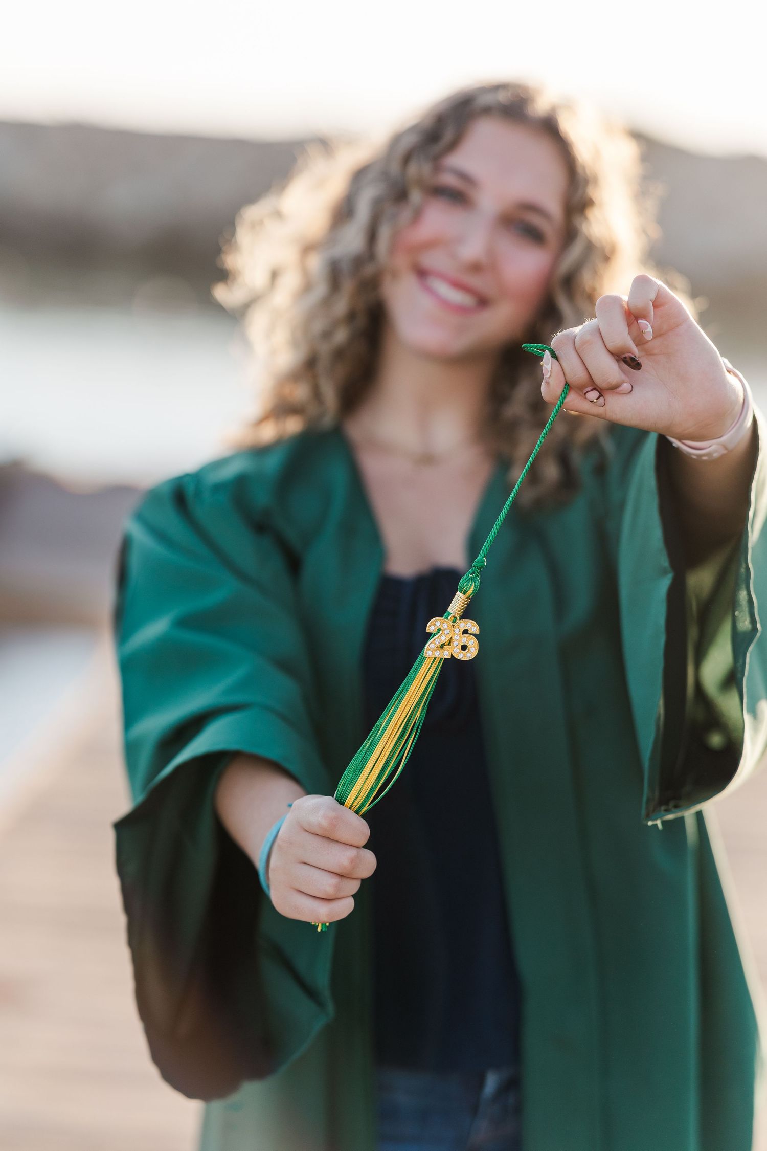 Close-up shots of someone in a green jacket holding graduation tassels.