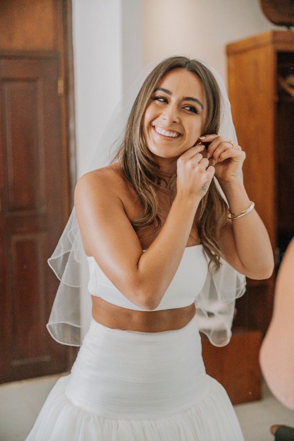 A bride in a white wedding dress laughs joyfully in a series of candid photos with warm lighting and wooden decor.