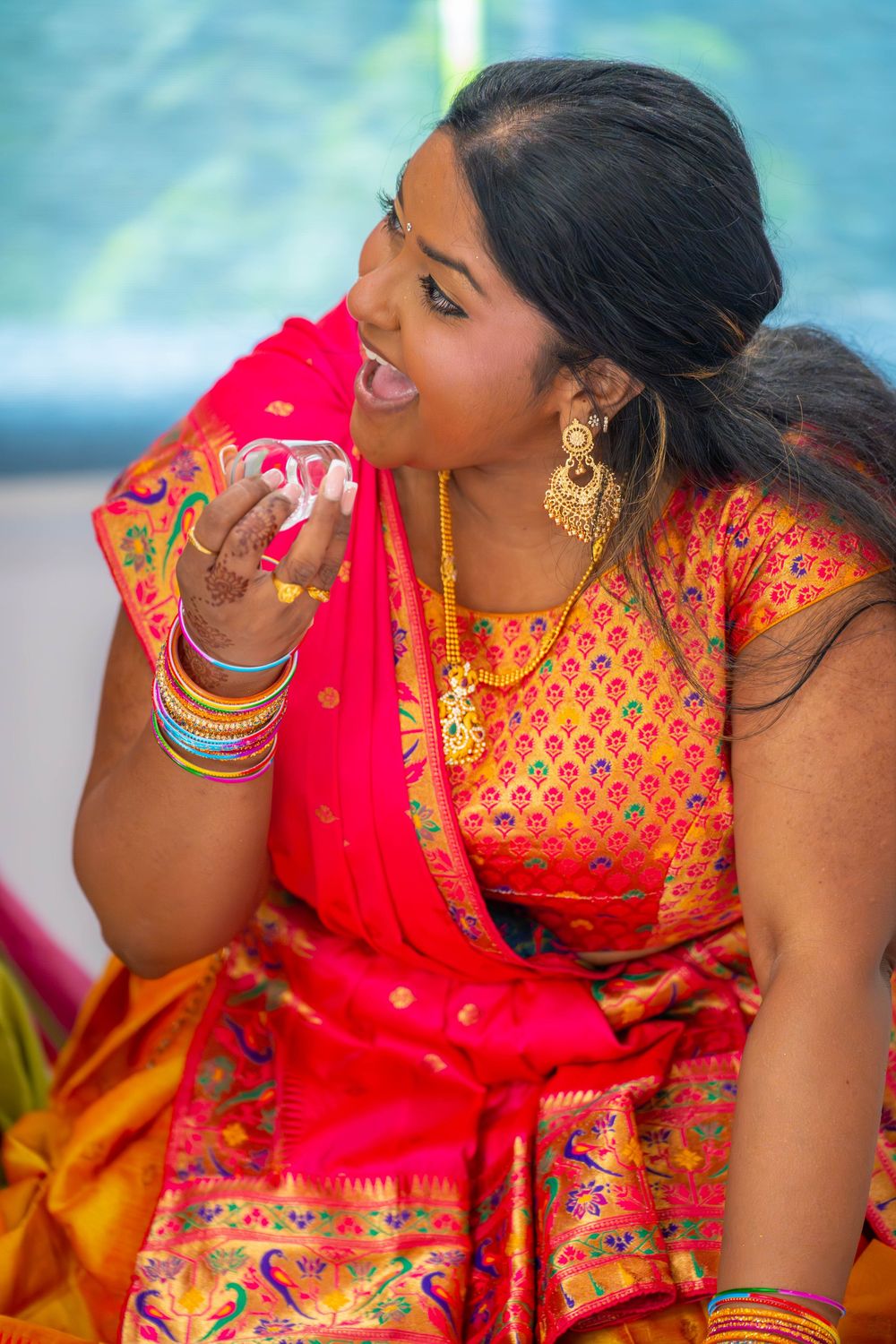 Woman in vibrant red and gold Indian attire poses playfully. Nischitartham Quad Cities Hindi Indian Photographer