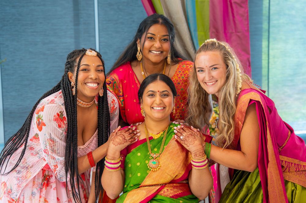 Group wearing colorful traditional Indian outfits smile together during cultural celebration.  Quad Cities Hindi Indian Photography