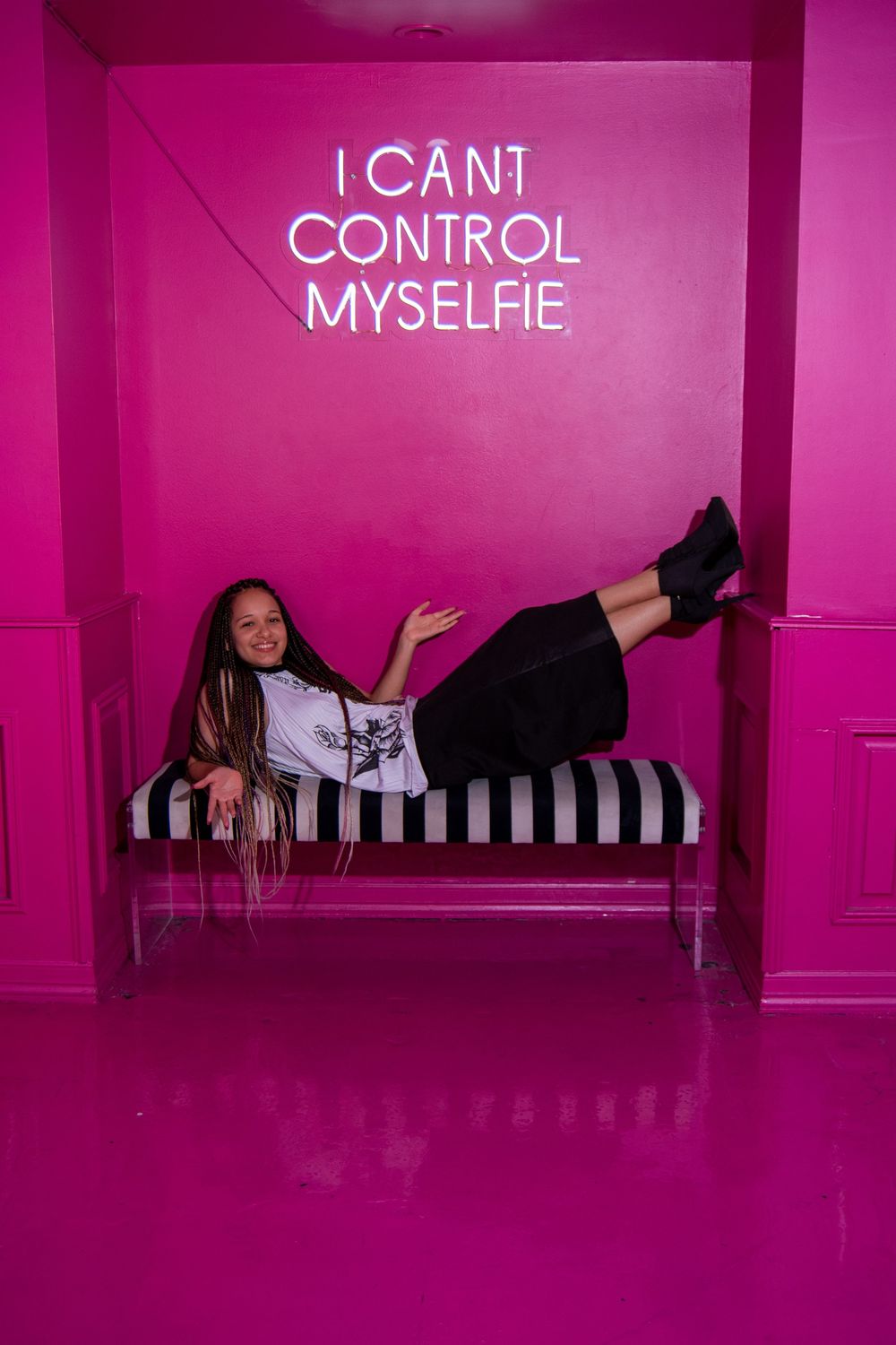 A person lies playfully on a bright pink reflective surface in a series of four progressive poses.