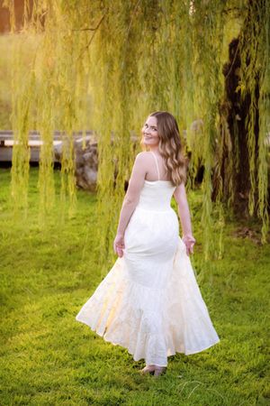 A white-dressed figure twirls through a garden beneath cascading willow trees in a series of joyful movement photos.