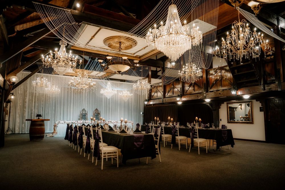 Elegant wedding venue with crystal chandeliers, draped ceilings, and long banquet tables set for a formal reception.