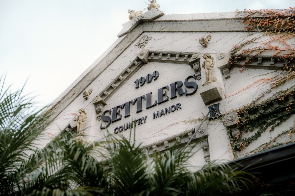 Settlers Country Manor 1909 historic white facade with ornate details and lush greenery in South Africa.