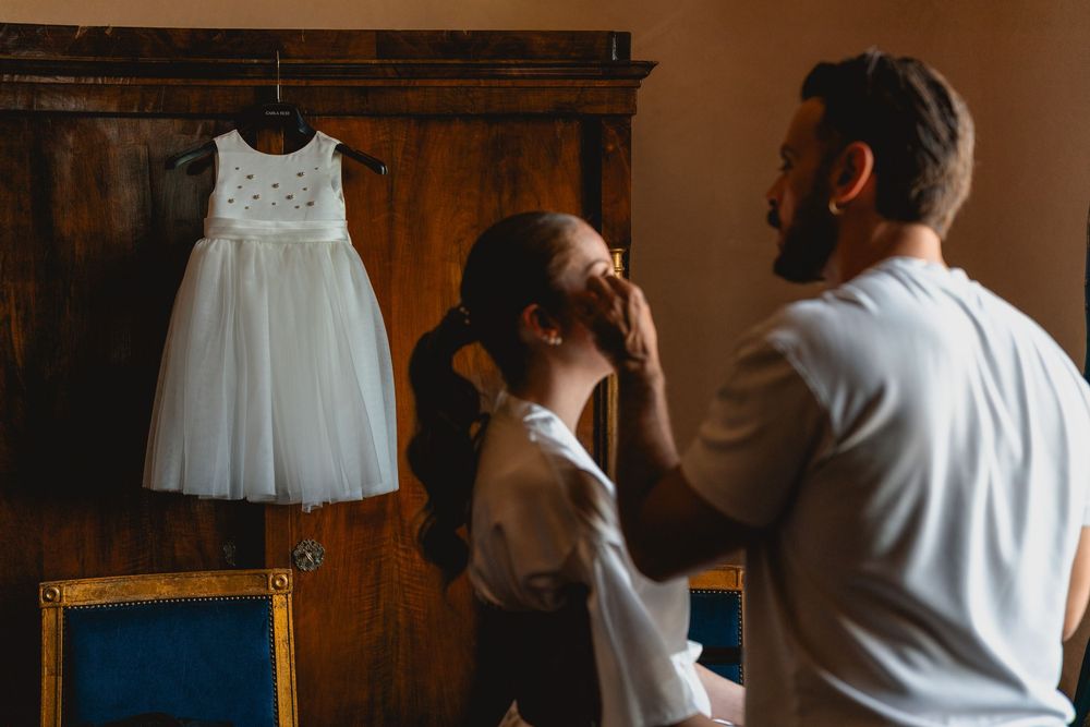 White wedding dress hanging in rustic wooden room during preparation.