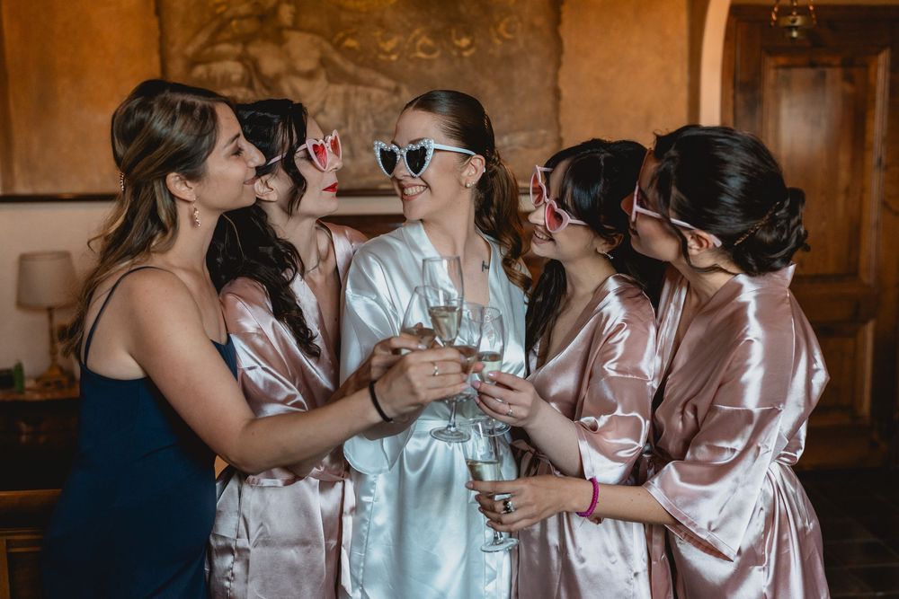 Bridesmaids in satin robes celebrating in a rustic venue setting.