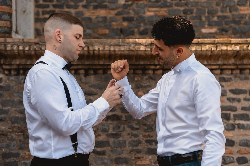 Wedding party members in white shirts and black ties helping each other get ready.