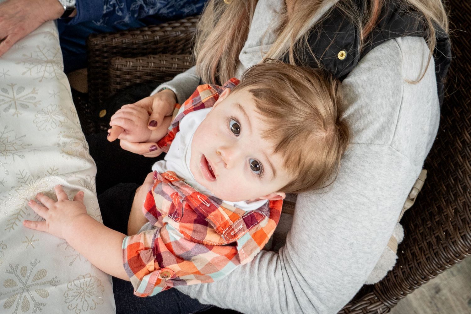 child looking up at the camera while being held in someone's lap