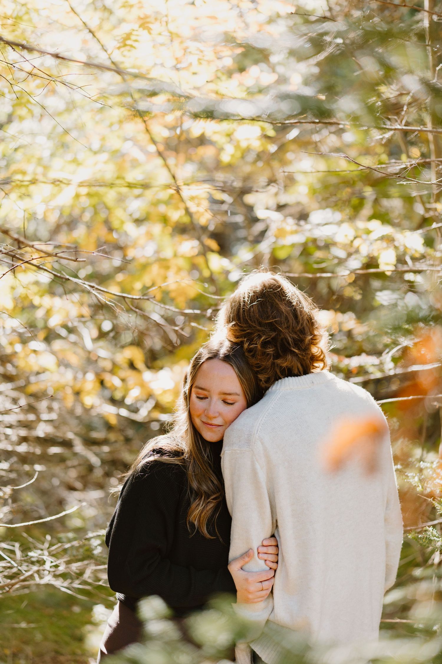 A close family shares an intimate moment together on a walking trail surrounded by evergreen forest.